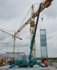 A Maeda crane on a construction site works alongside tower cranes.